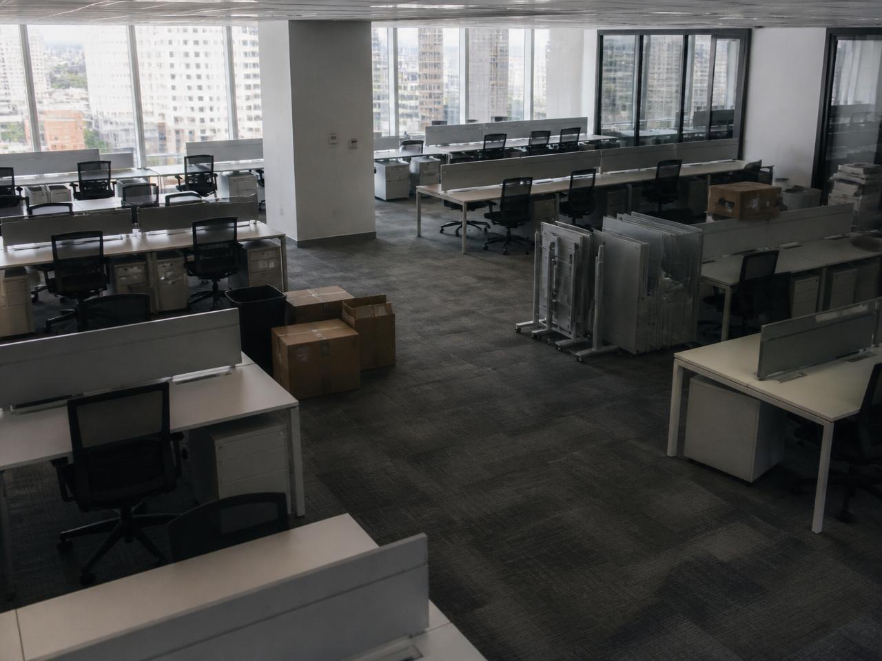 Halbleeres Büro mit ungenutzten Arbeitsplätzen, Stühlen und Umzugskartons